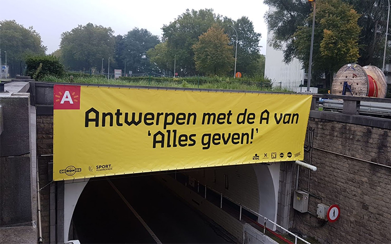 Een banner van stad Antwerpen hangt boven een brug. De banner is van het materiaal frontlit.