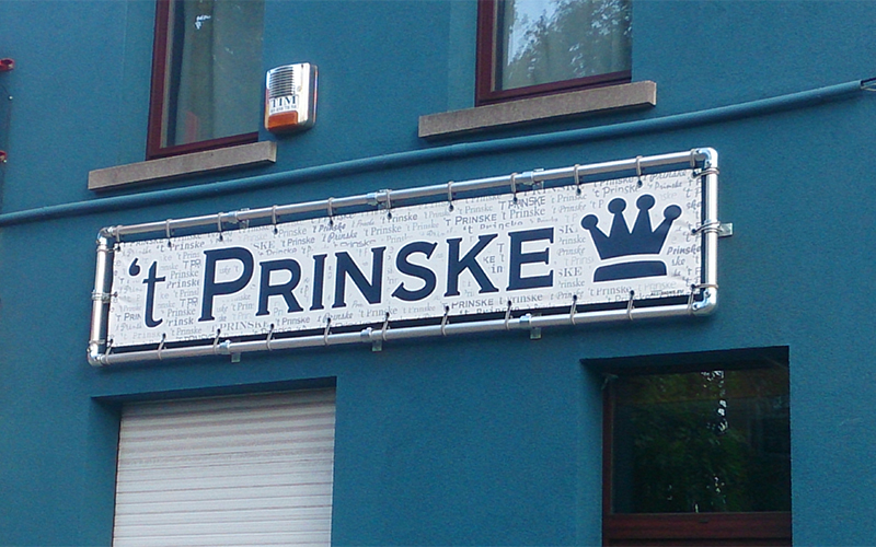 Een banner met de naam 't Prinske hangt op de gevel van een gebouw.