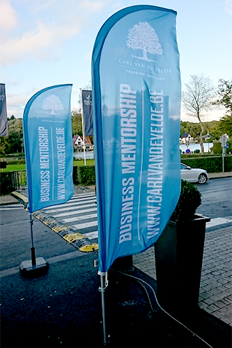 Beachvlaggen die voor de ingang van een event van Carl Vandevelde staan.